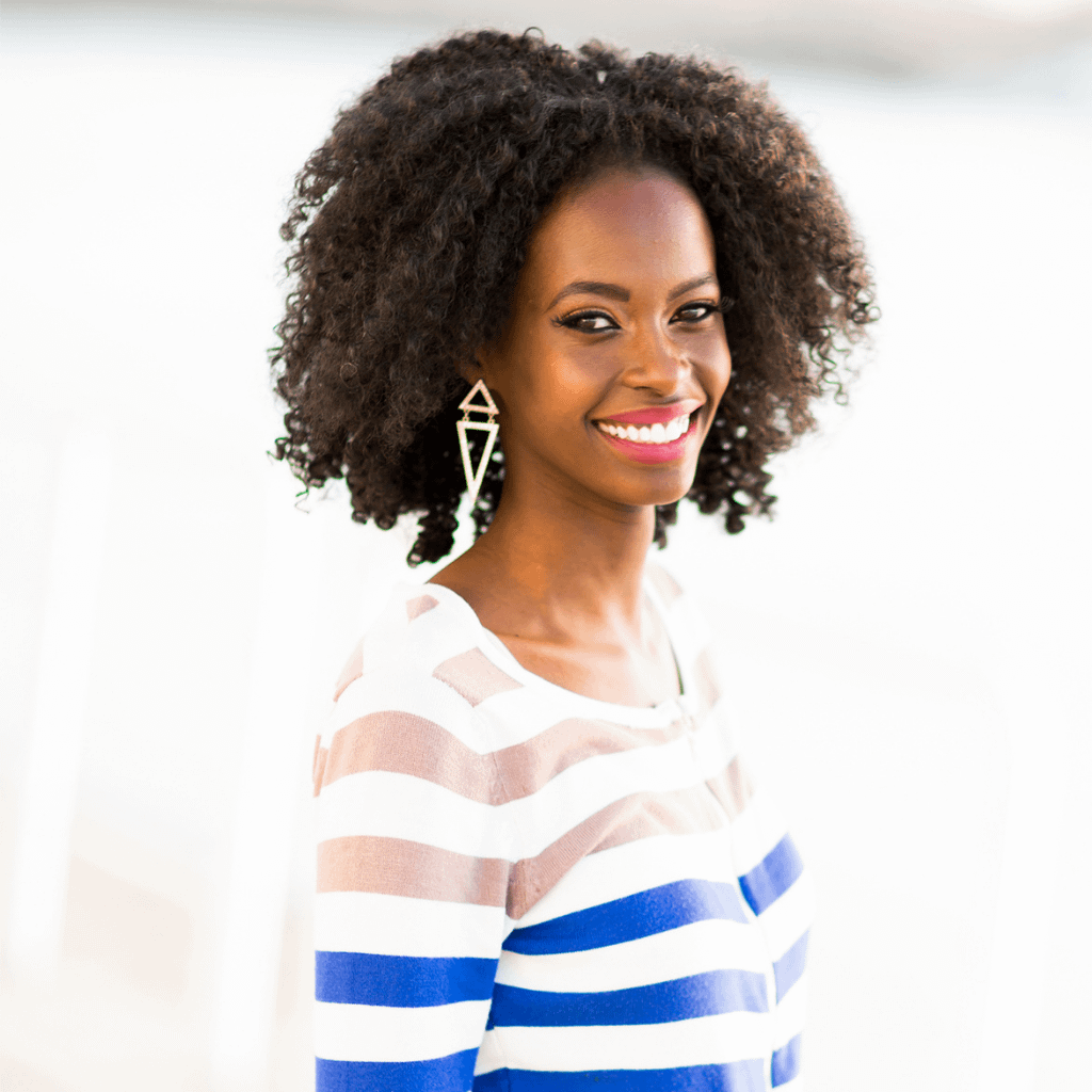 a woman with curly hair smiling confidently into the camera