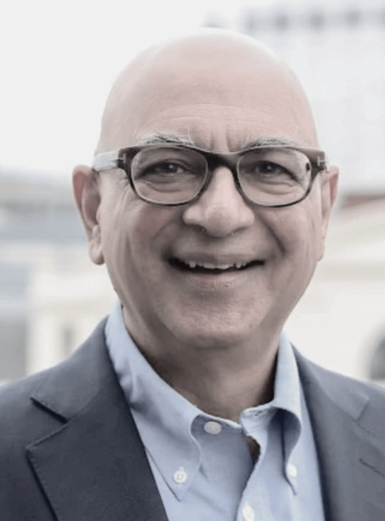 Latif Sayani standing confidently in a suit outside, smiling